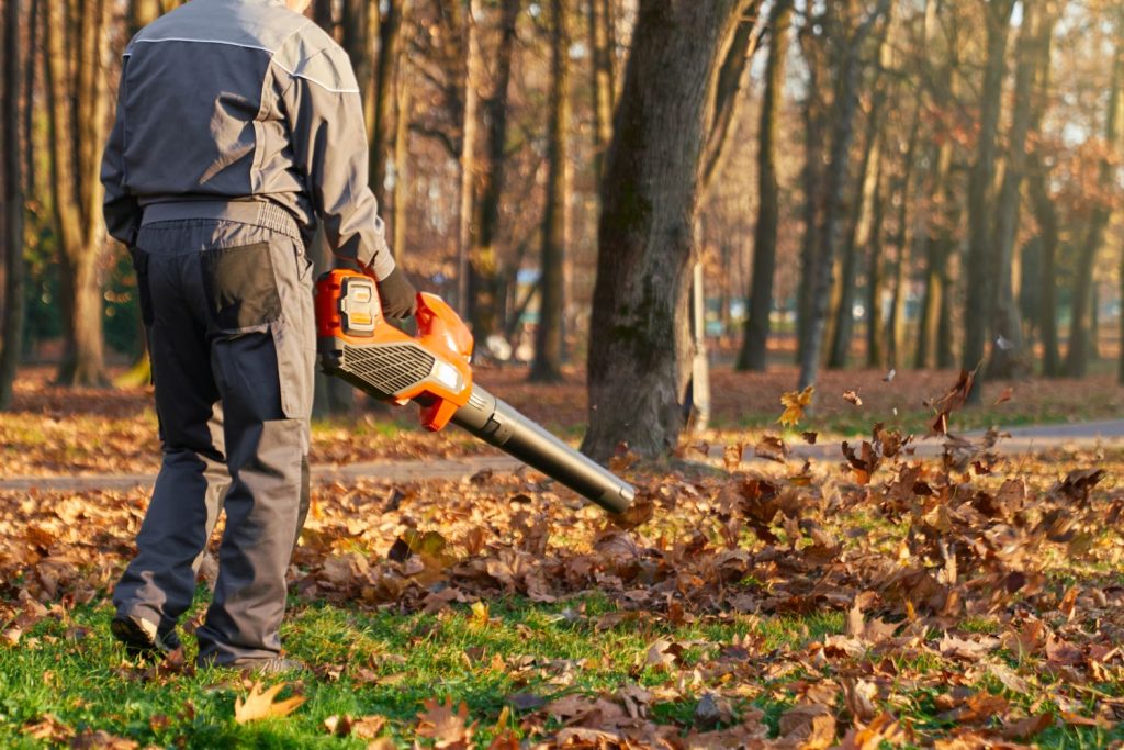 Arbeiter entfernt Laub mit einem Laubbläser im Park